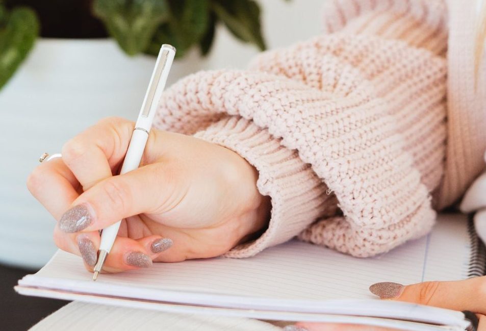 Midlife woman writing in a notebook, planning SEO strategies for her online business growth.